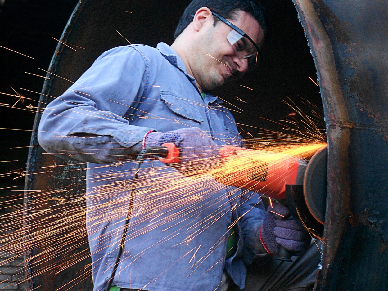 Trabajador restaurando vieja locomotora de vapor